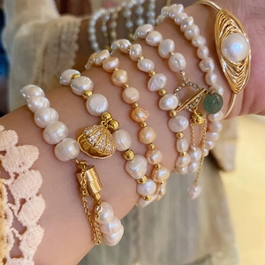 Detail of layered freshwater pearl bracelet with gold tassel and shell charm accents