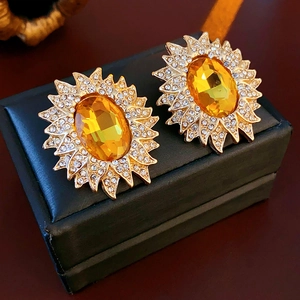 Detail of vintage sunburst earrings with yellow crystal inlay on a black display box
