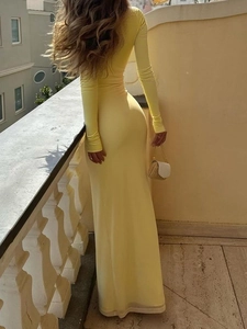 Elegante abito lungo giallo a maniche lunghe con vista posteriore aderente sul balcone