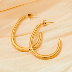 Macro detail of the golden U-shaped crescent earrings on soft beige velvet fabric