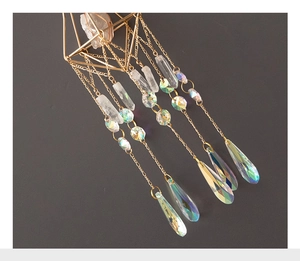 Macro shot of geometric crystal suncatcher showing iridescent rainbow prisms on grey background