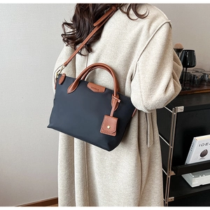 Detail of waterproof nylon tote with brown leather handles and adjustable shoulder strap