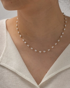 Close-up of minimalist gold chain necklace with delicate white pearls on model's neckline
