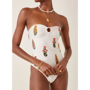 Détail d'un maillot de bain bandeau blanc avec broderie florale et anneau doré central