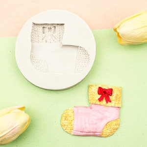 Detail of boot-shaped silicone mold with pink and yellow knitted texture and red bow