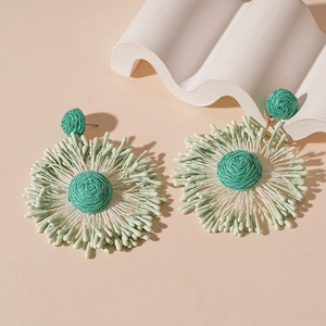 Handmade woven flower drop earrings in green and white with a boho vacation style look