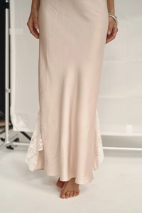 Detail of champagne satin maxi dress featuring elegant white lace trim at the bottom hem