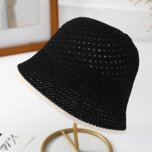 Breathable black hollow knit bucket hat with cream trim shown on elegant display stand