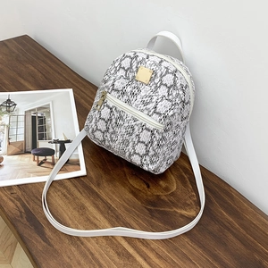 Detail view of mini backpack featuring black and white snakeskin pattern and gold hardware