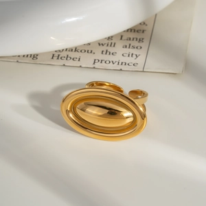 Close-up of a minimalist golden oval signet ring with a polished mirror finish on white table