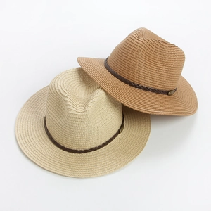 Close-up of woven straw fedora hats with dark brown bands and gold metal buckles