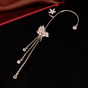 Makroaufnahme von goldenem Schmetterling-Ohrclip mit Zirkon-Blumen und Fransen