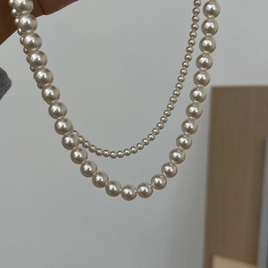 Detailed view of layered white pearl necklace showing dual sizes of lustrous beads