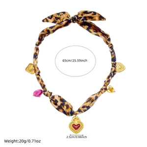Detail view of leopard print silk scarf necklace with golden heart charms and sizing data