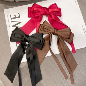 Detail view of large silk bow hair clips in wine red, black, and brown with long ribbons