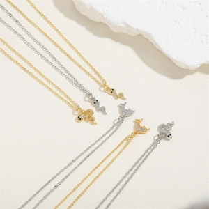 14K gold plated serpent and dolphin zircon pendant necklaces on textured background