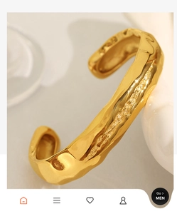 Macro detail of golden irregular lava texture on an adjustable metal open cuff bracelet