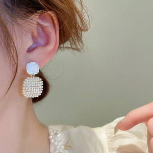 Detailed close-up of light blue gemstone and faux pearl square drop earrings on model