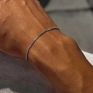 Minimalist silver stainless steel snake chain bracelet worn on wrist in sunlight