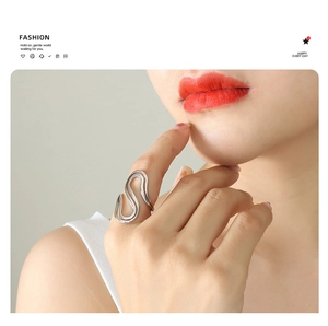 Detailed view of polished S-shaped wavy silver ring worn on female model finger