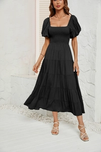 Détail de robe noire à manches bouffantes, jupe à volants et décolleté carré au soleil
