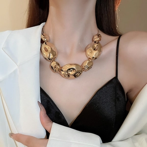 Detailed view of bold abstract golden necklace with wrinkled metallic rings on a model