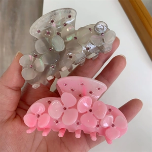 Detail of floral acetate hair claws with sparkling rhinestones in grey and pink finish