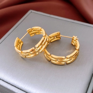 Macro shot of gold-plated geometric hollow hoop earrings with a textured chain design