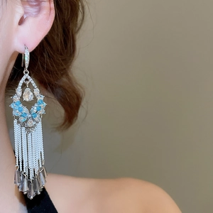 Detail of silver needle earrings featuring sky blue crystal flowers and long metal tassels