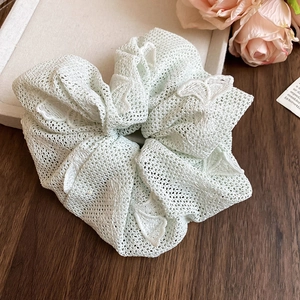 Détail du chouchou en dentelle vert menthe montrant la texture délicate du tissu fleuri