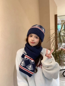 Dettaglio del berretto in maglia blu scuro con strisce rosse e motivi di fiocchi di neve