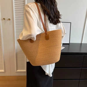 Women's large khaki woven tote bag with leather straps in a minimalist home setting