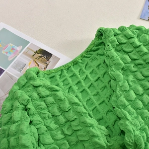 Close-up of bright green bubble texture fabric on a two-piece cutout outfit