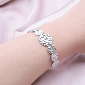 Macro view of silver C-shaped stainless steel cuff with hammered texture and matte finish