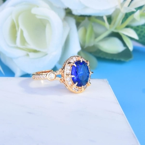 Macro shot of luxury gold ring with oval sapphire blue stone and diamond halo