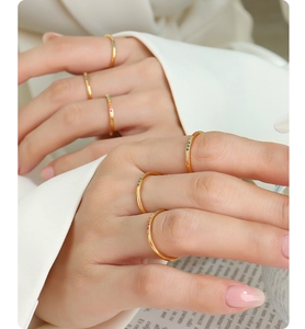 Detailed close-up of gold slim rings featuring colorful zircon stones worn by a model
