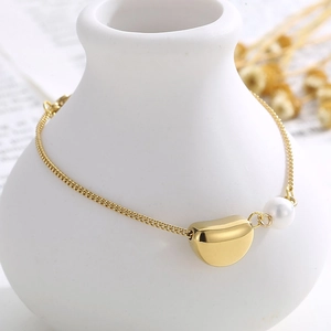 Détail d'un pendentif haricot doré et d'une perle blanche sur un bracelet élégant