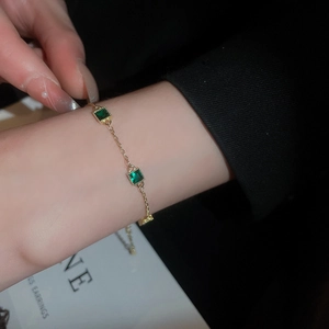 Gros plan détaillé d'un bracelet plaqué or serti de deux pierres vert émeraude carrées