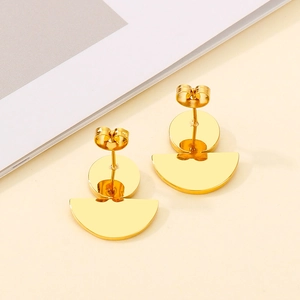 Detail of polished gold half-round geometric stud earrings on a minimalist background