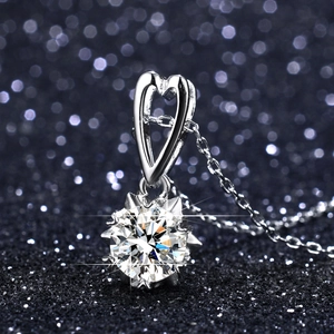 Macro view of a 1-carat moissanite necklace with a heart-shaped bail on a blue starry background