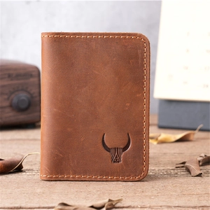Close-up of vintage brown leather card holder with bull head logo on wooden desk