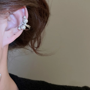 Close-up of elegant curved pearl ear cuff with four gradient pearls on silver metal