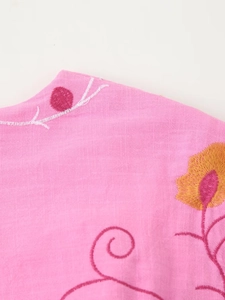 Detailed embroidery on pink cotton linen fabric with floral patterns and stitching