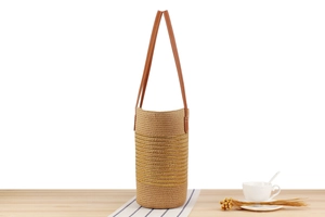 Detailed close-up of straw woven tote with gold thread and brown leather strap