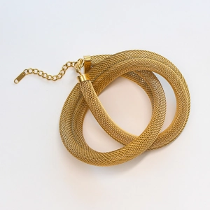 Close-up of golden mesh chain necklace showing woven texture and lobster clasp detail