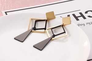 Detailed view of long geometric earrings with gold and black square metal pendants