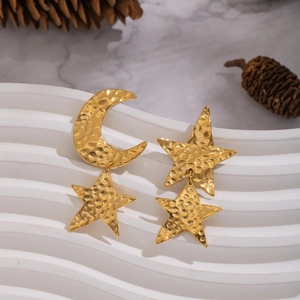 Close-up of gold hammer textured moon and star stud earrings on white pedestal