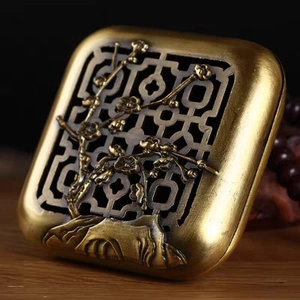 Macro shot of an antique brass incense burner lid with plum blossom carvings and cutout