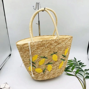 Detail of hand-woven straw bag featuring yellow lemon embroidery and drawstring closure