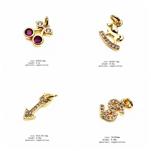 Detail of four gold zircon charms including cherry and rocking horse shapes for jewelry making